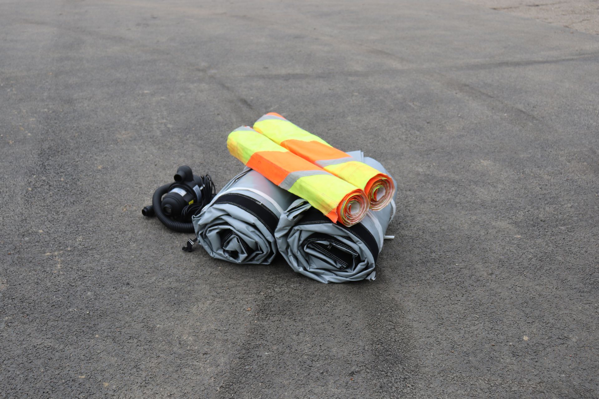 Two InflatorShield units rolled and compact on tarmac beside a blower, ready to be positioned
