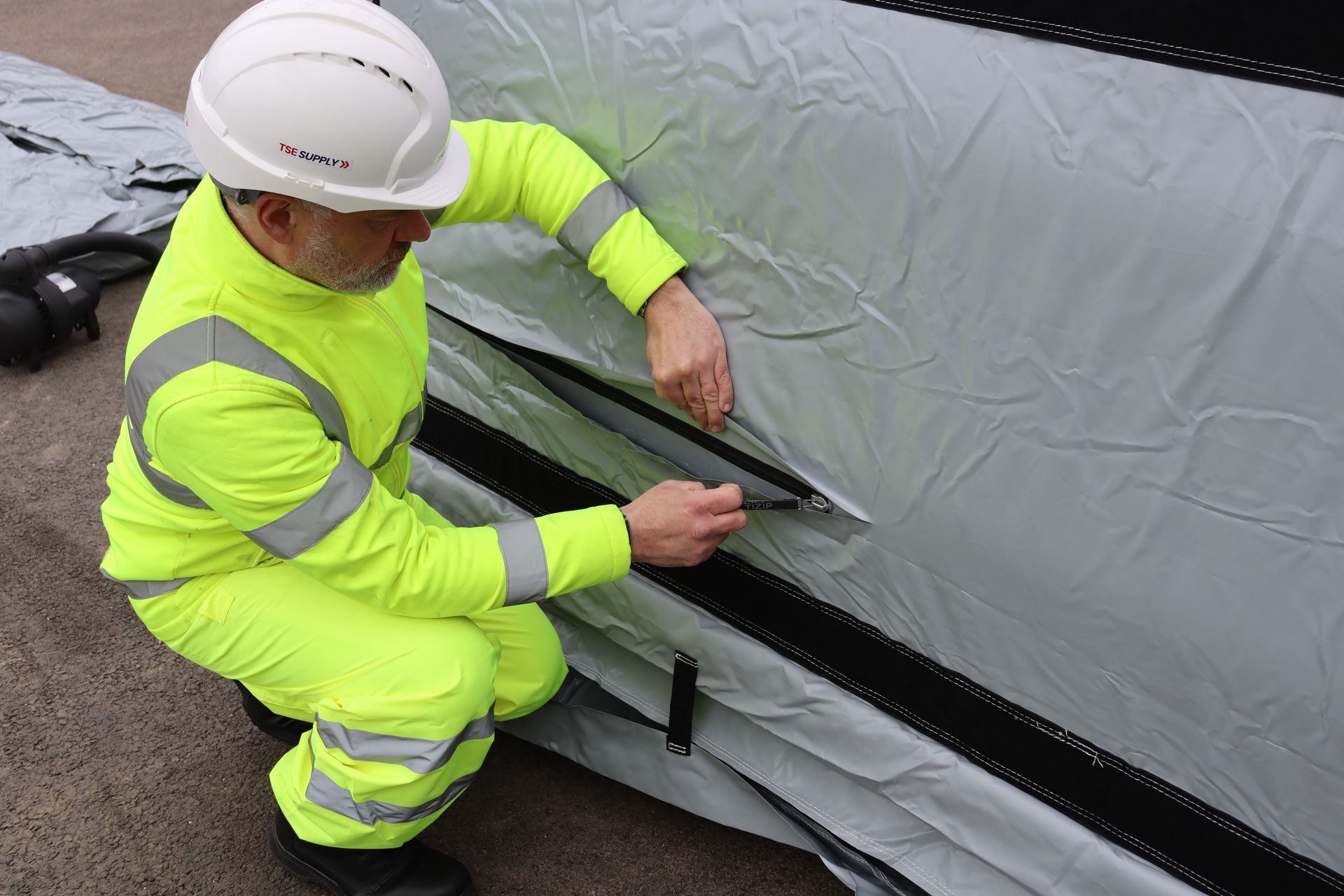 Operative opening the TiZIP quick-release zip to deflate an InflatorShield unit — takes seconds