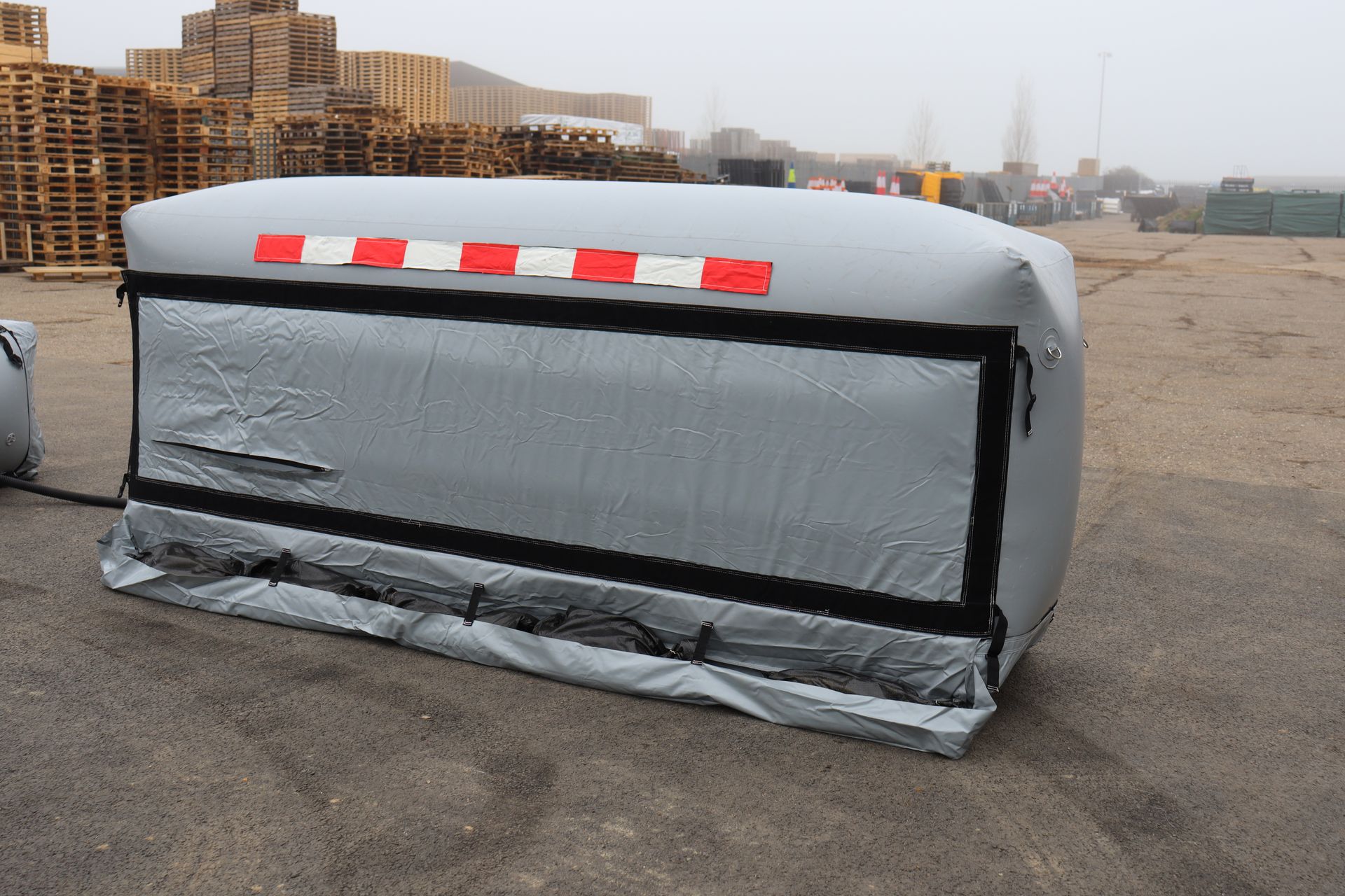 Single InflatorShield unit fully inflated, side view showing grey tubular form with red/white front panel